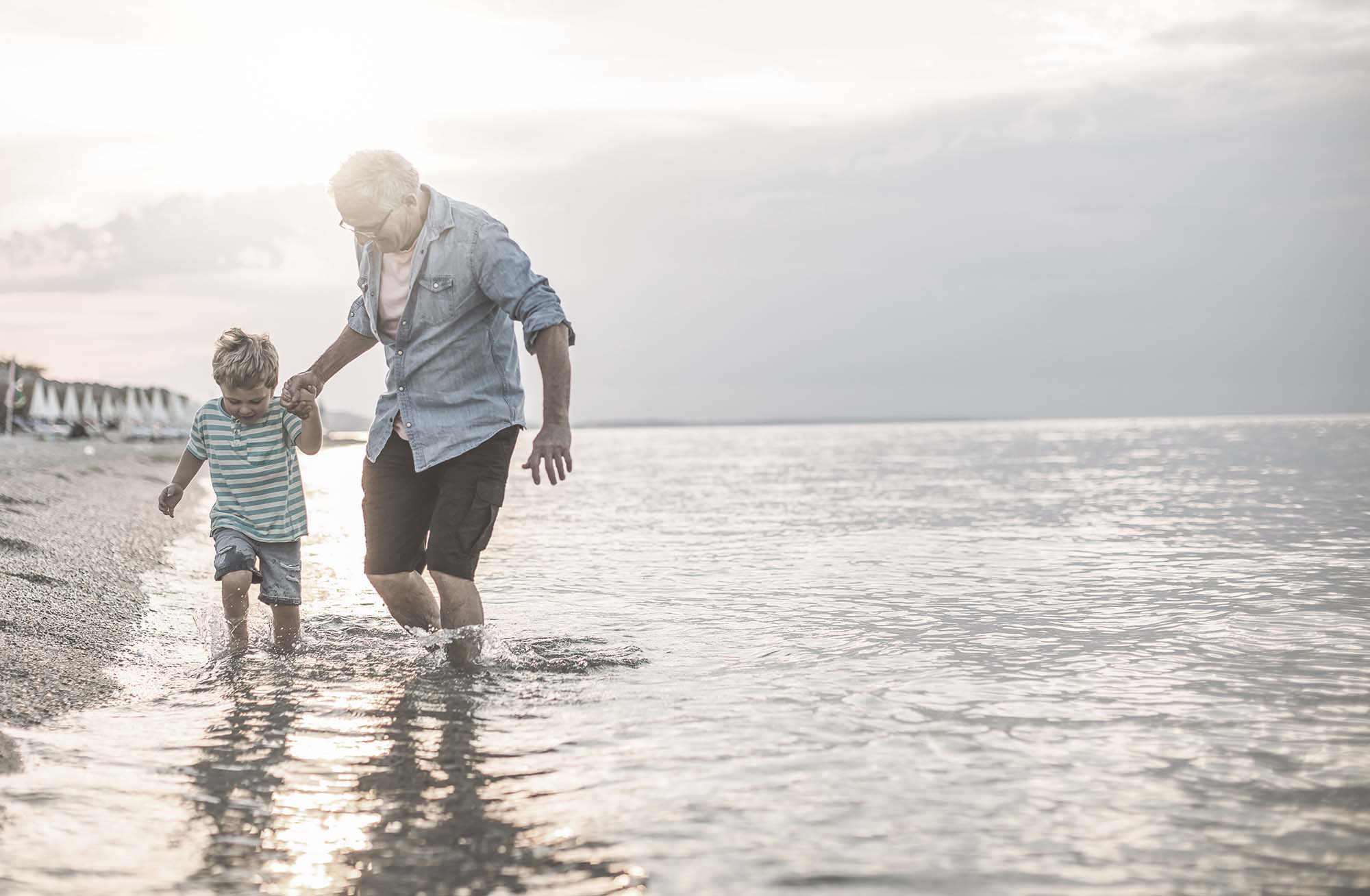 Man playing in water on a beach with boy